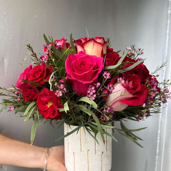 Pink and red roses arranged in a white vase