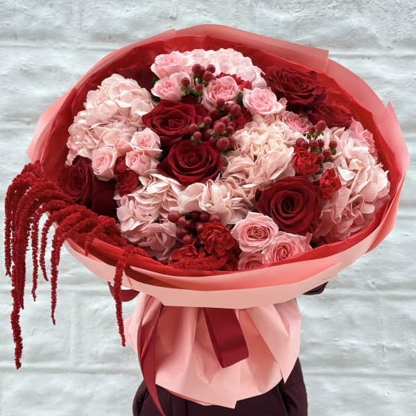 Bouquet of red and pink roses with hydrangeas wrapped in pink paper
