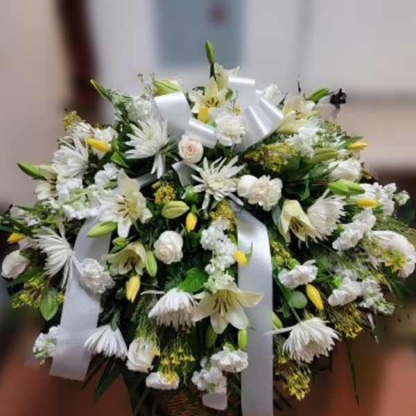White floral spray with lilies and daisies tied with white ribbon