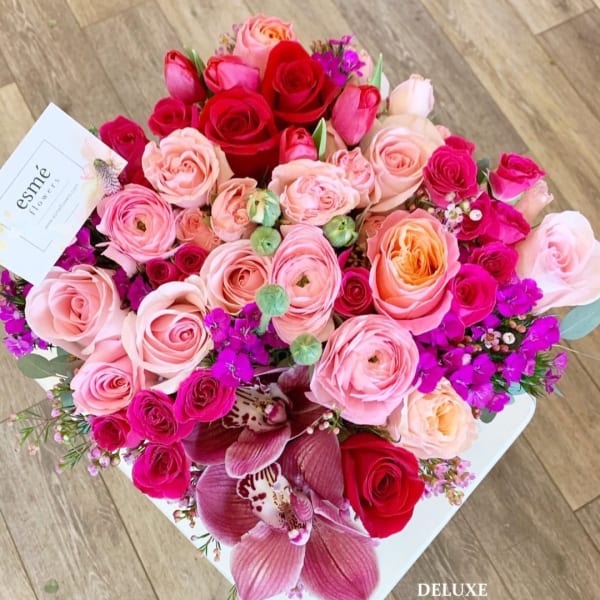 Bouquet of pink and red roses with purple orchids in a white box