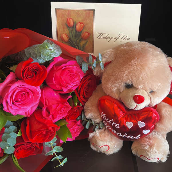 Bouquet of red and pink roses with a teddy bear holding a heart