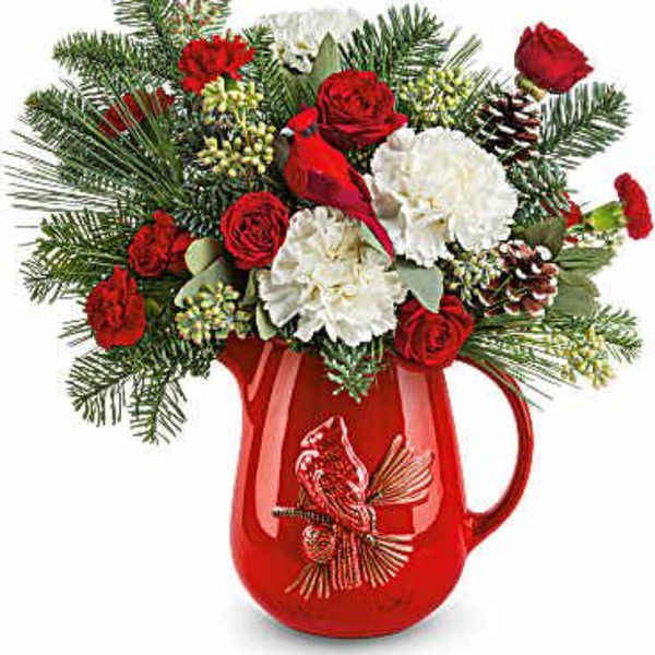 Red and white floral arrangement in a red pitcher vase