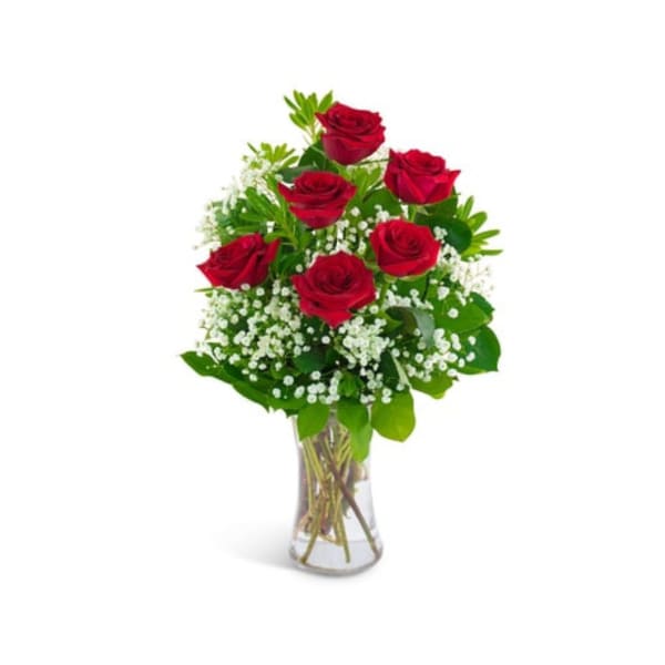 Red roses arranged in a clear glass vase with white filler flowers