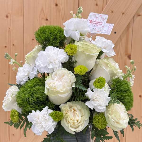 White roses and carnations in a glass vase with green pom-pom accents