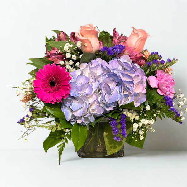 Mixed bouquet with hydrangea, roses, and gerbera daisies in a glass vase