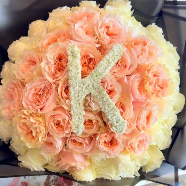 Round bouquet of peach and cream roses with a floral letter K