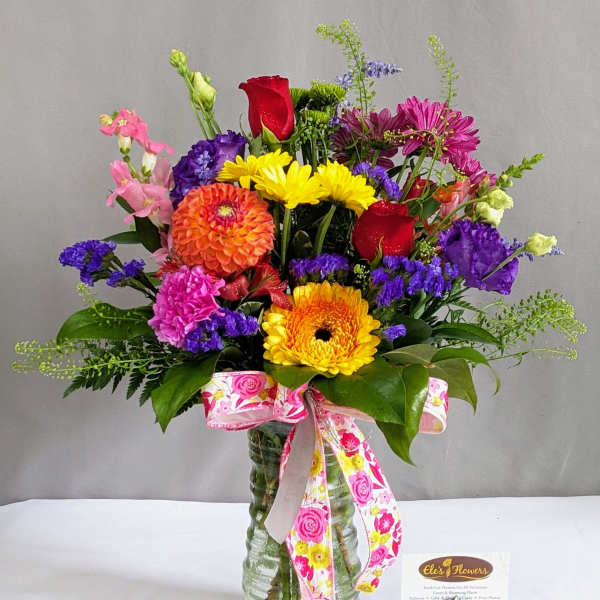 Colorful mixed bouquet in a glass vase with a pink ribbon