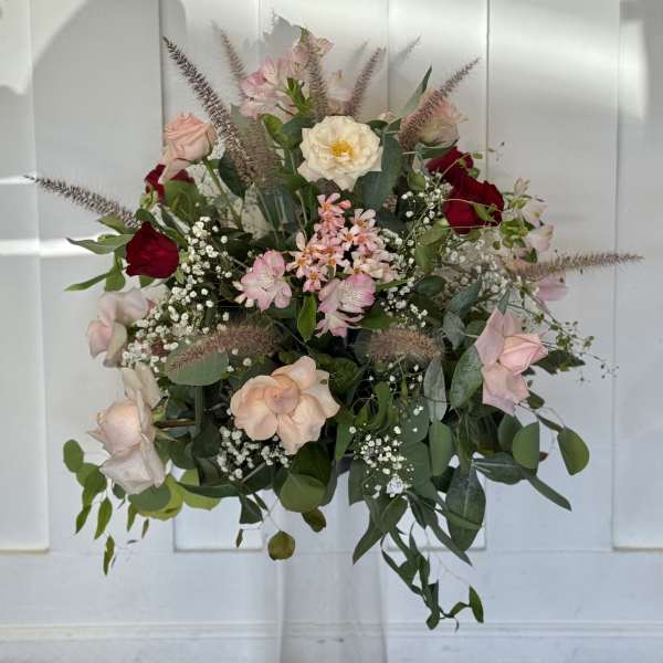 Mixed pink and red roses in a clear pedestal vase