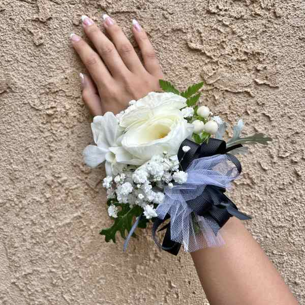 White wrist corsage with ribbon and small berries on a hand