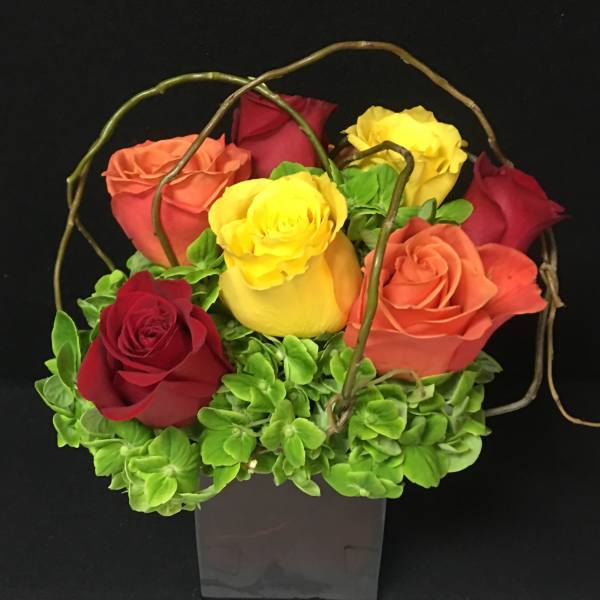 Bouquet of multicolored roses in a square vase
