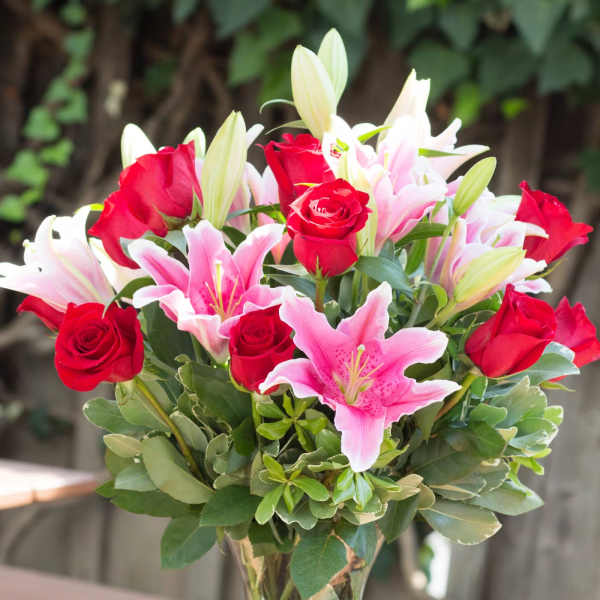 Bouquet of red roses and pink lilies in a clear glass vase