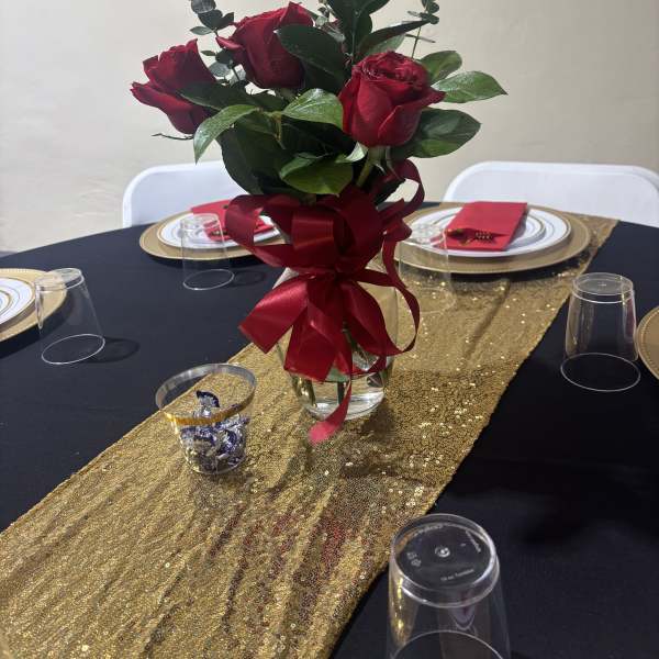 Red roses in a glass vase with a red ribbon on a decorated table