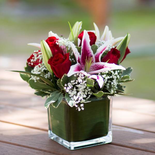 Red roses and white lilies in a square glass vase