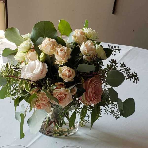 Blush and white roses in a clear glass vase with eucalyptus