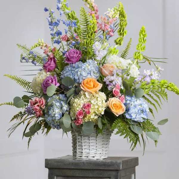 Colorful mixed flower arrangement in a white wicker basket