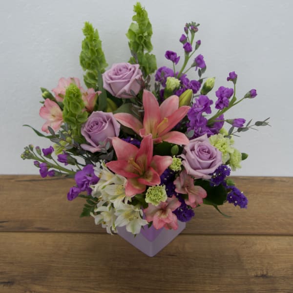 Mixed bouquet with pink lilies, lavender roses, and purple flowers in a lavender box