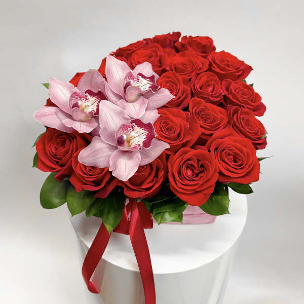 Red roses with pink orchids in a white box tied with a red ribbon