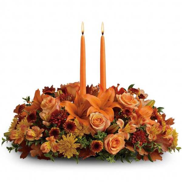 Orange floral centerpiece with two taper candles