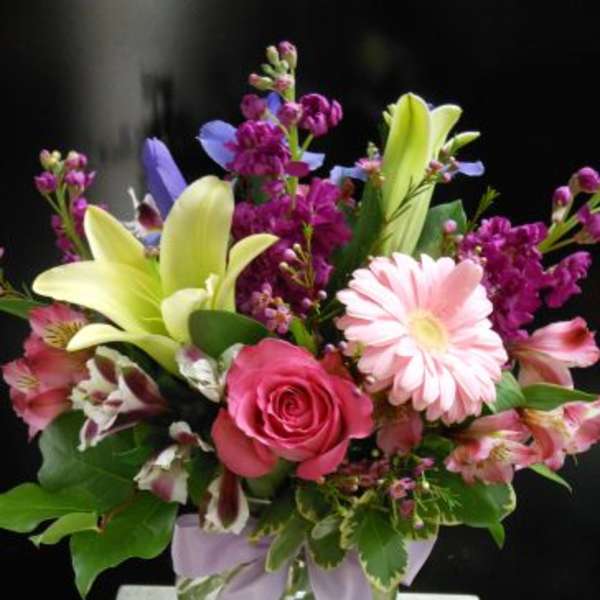 Mixed bouquet with pink roses, lilies, and a pink daisy in a glass vase
