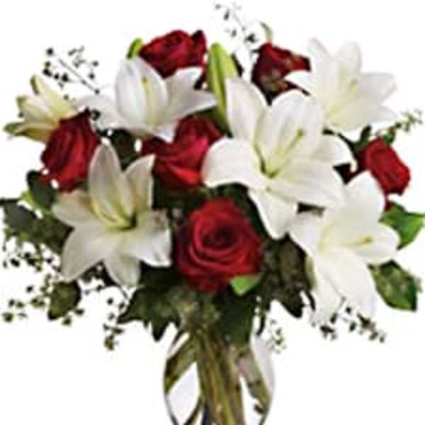 Bouquet of red roses and white lilies in a clear vase