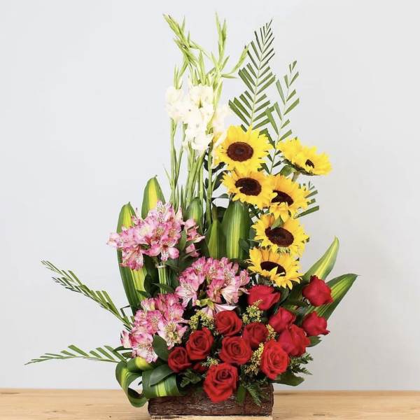 Tall mixed flower arrangement with red roses, pink alstroemeria, and sunflowers