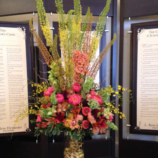 Tall mixed floral arrangement in a clear glass vase with pink and orange blooms