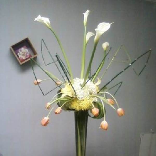 Tall floral arrangement with white calla lilies and peach tulips in a vase