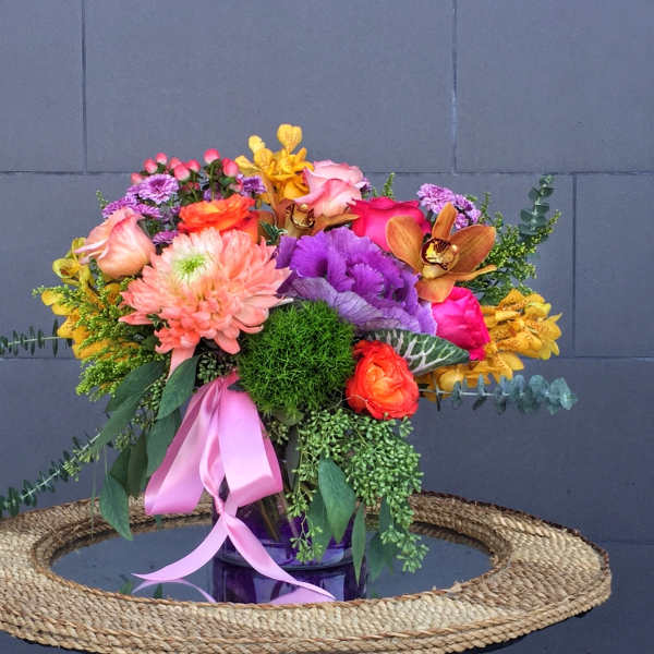 Colorful mixed bouquet in a glass vase with a pink ribbon
