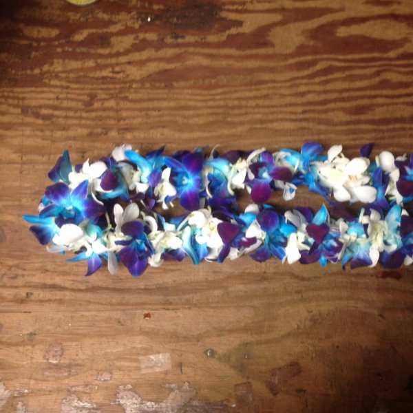 Blue, purple, and white flower lei on a wooden surface