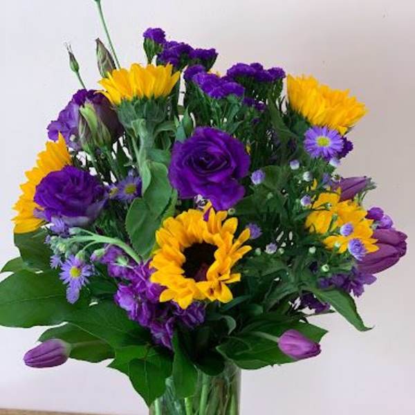 Bouquet of purple and yellow flowers in a clear glass vase