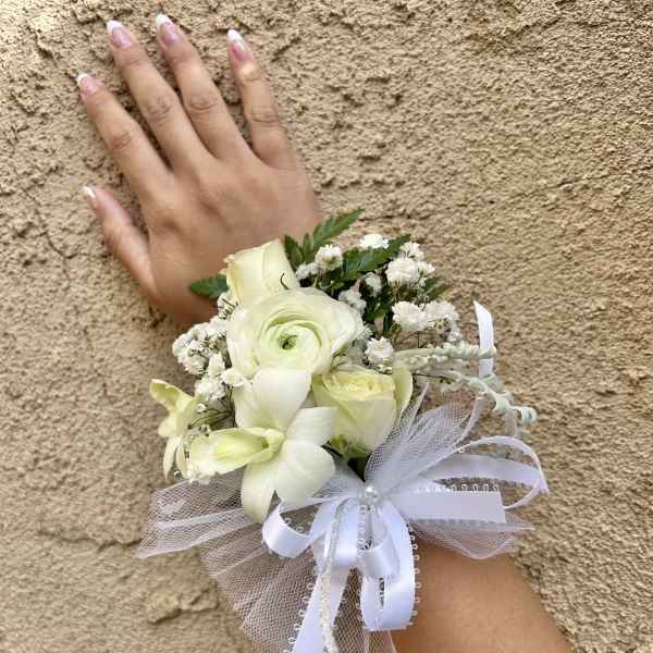 Small white wrist corsage with roses and ribbon
