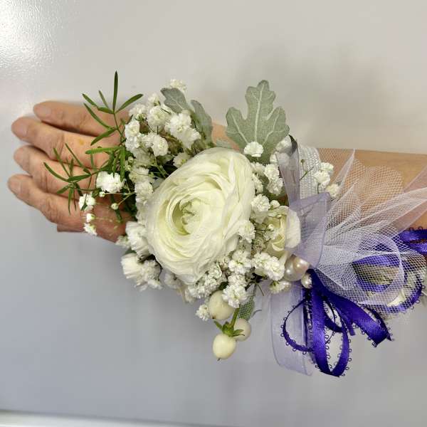 White ranunculus corsage with baby's breath and purple ribbon