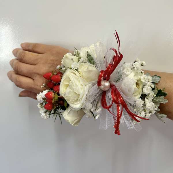White floral wrist corsage with red ribbon and berries