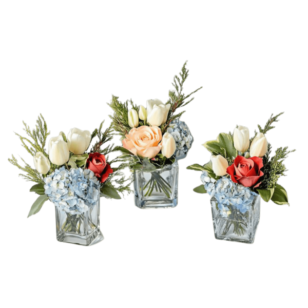 Three small floral arrangements in square glass vases with tulips, roses, and hydrangeas.