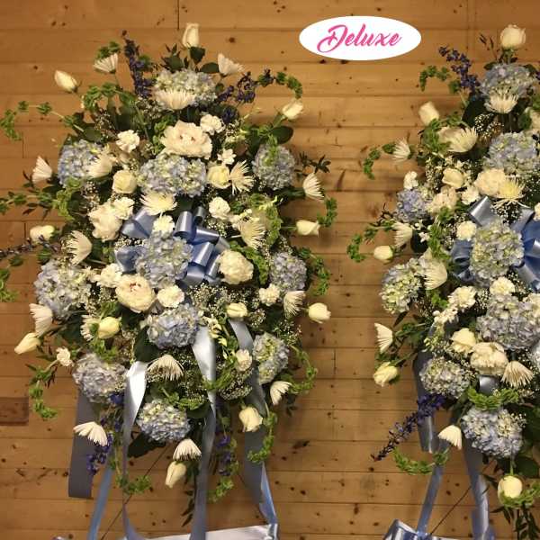 Two large blue and white floral standing sprays with ribbon bows