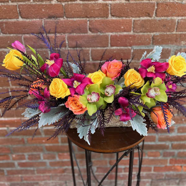Bright mixed floral arrangement with roses and orchids on a small table