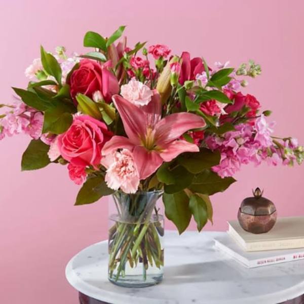 Pink roses and lilies arranged in a clear glass vase