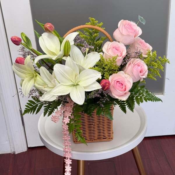 Basket arrangement of pink roses and white lilies