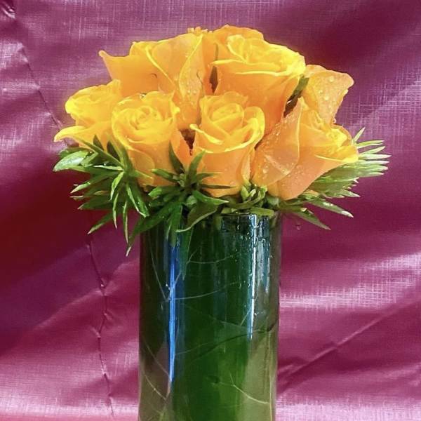 Orange roses arranged in a tall glass vase