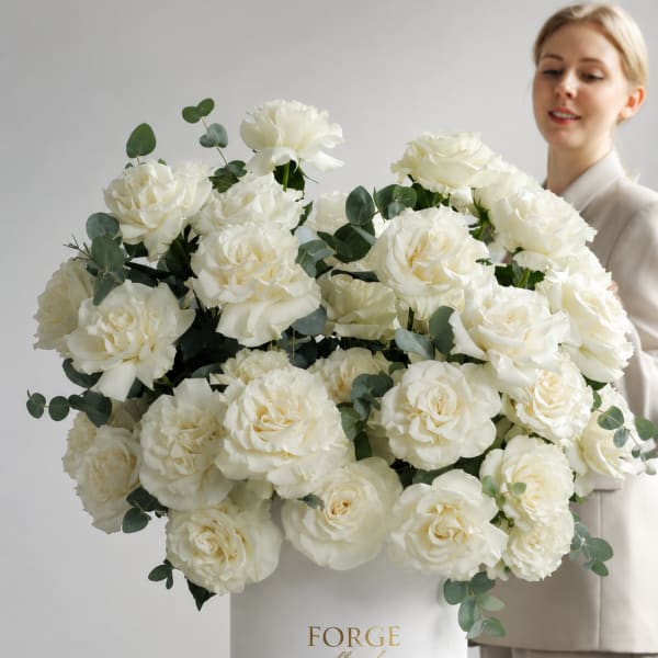 Large white rose arrangement in a white hat box with eucalyptus