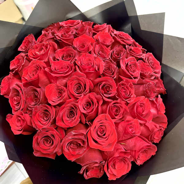 Large bouquet of red roses wrapped in black paper