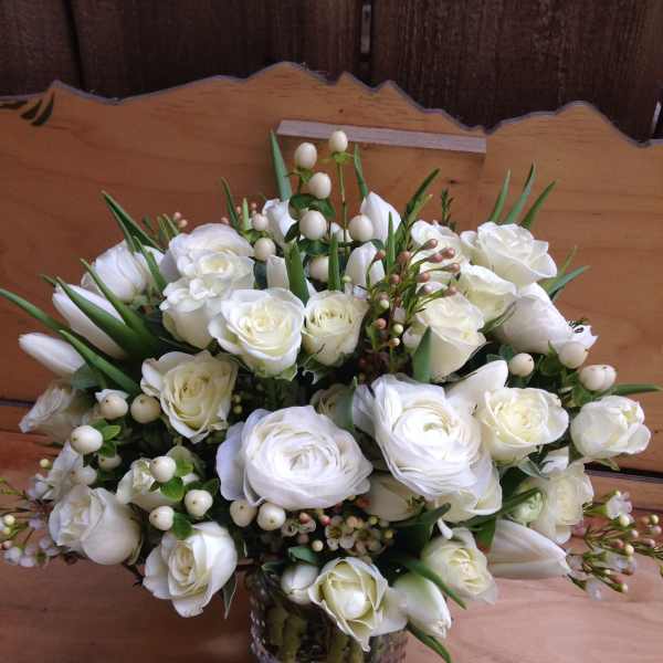 White rose bouquet in a glass vase with berry accents