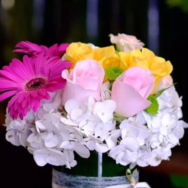 Mixed bouquet in a green vase with pink, yellow, and white flowers
