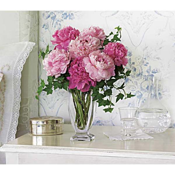 Pink peony bouquet in a clear glass vase on a table
