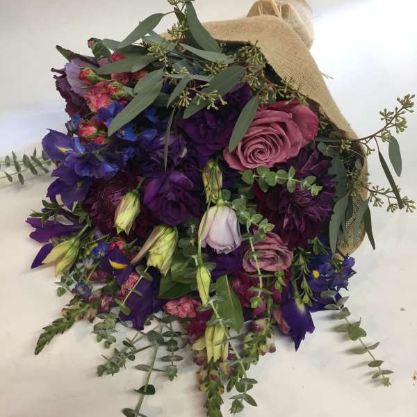 Bouquet of purple and pink flowers wrapped in burlap