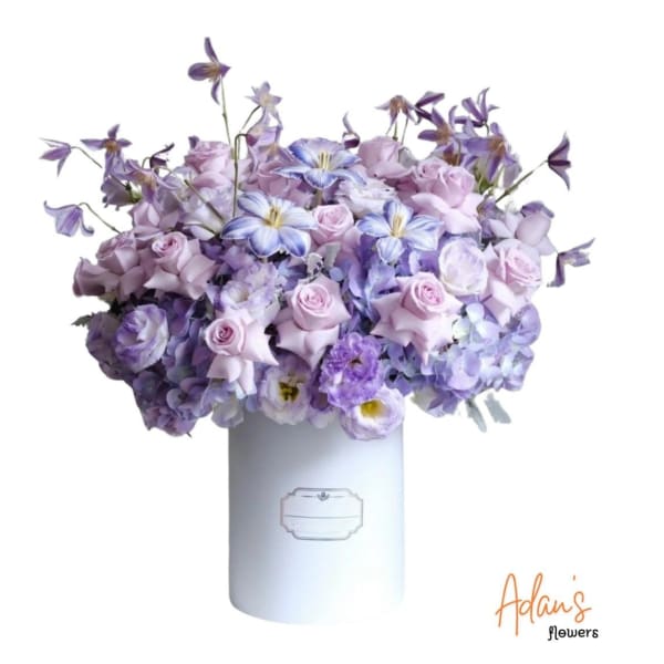 Lavender and purple bouquet in a white cylindrical box