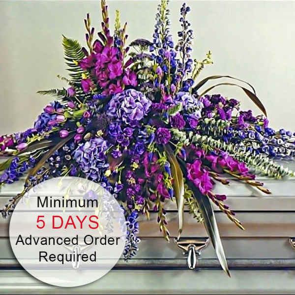 Long purple and pink floral casket spray arranged on a silver casket.