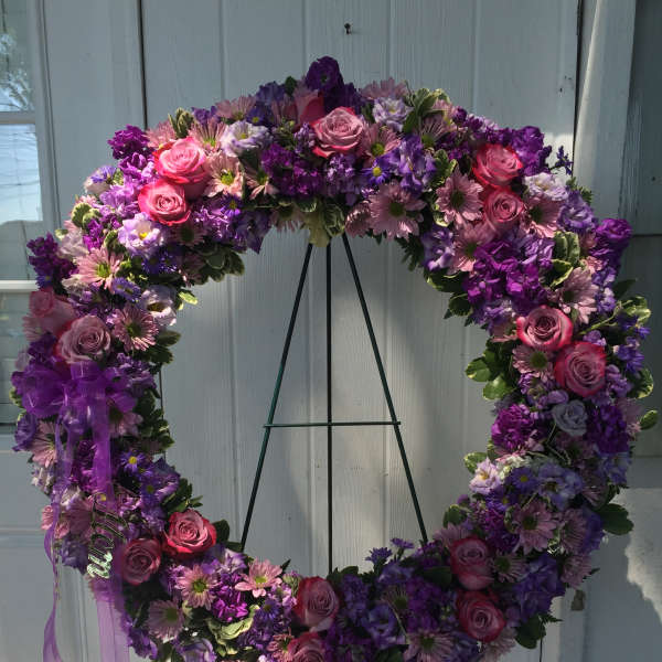 Heart-shaped floral wreath with pink and purple flowers on a stand