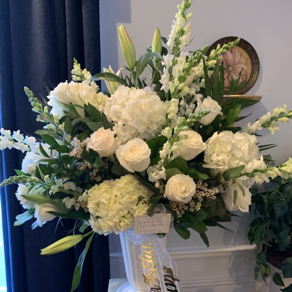 Large white floral arrangement in a pedestal vase