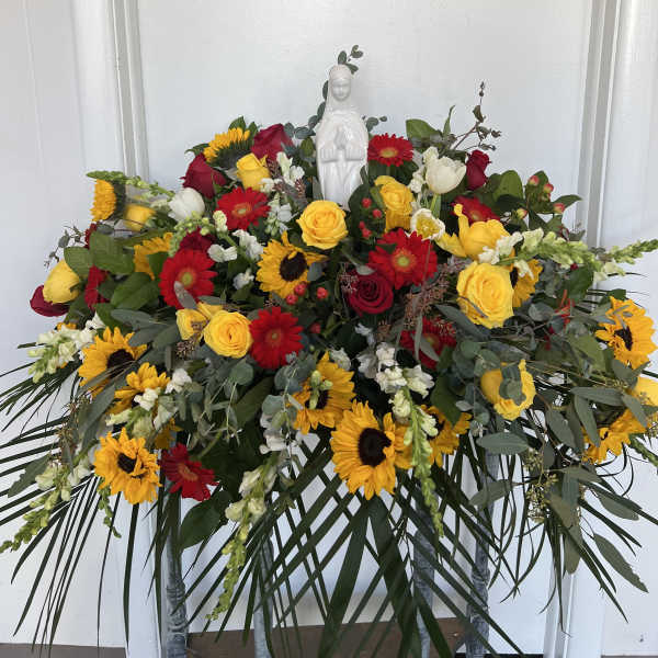 Large floral spray with red, yellow, and white flowers around a white statue